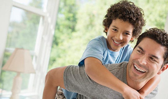 A man gives a piggyback ride to a smiling boy.